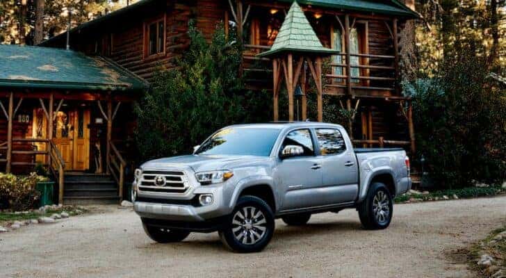 A silver 2021 GMC Canyon is shown parked near a cabin after visiting a used truck dealer.