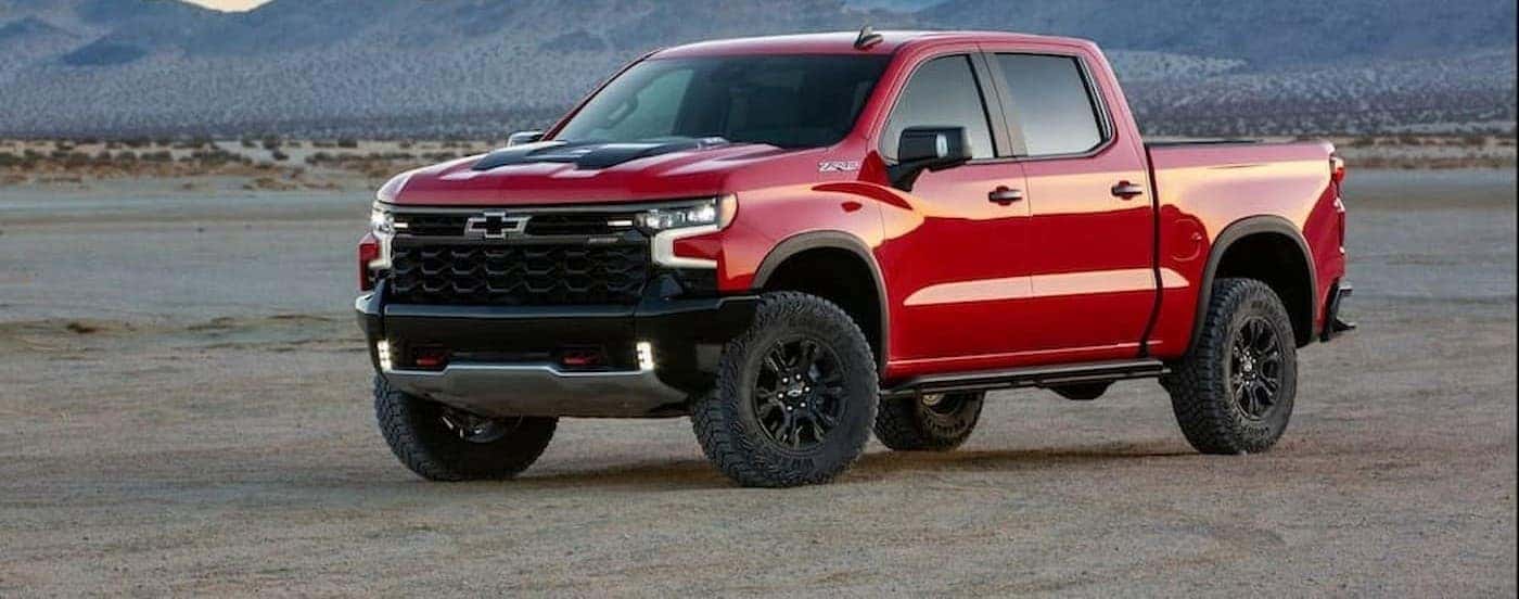 A red 2022 Chevy Silverado 1500 ZR2 is shown parked off-road near mountains.