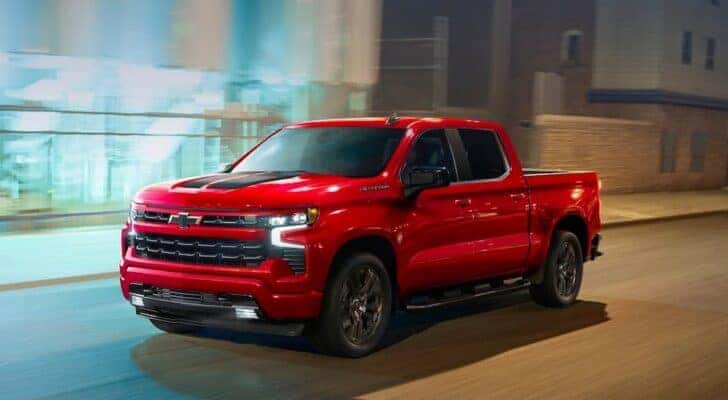 A red 2023 Chevy Silverado 1500 RST is shown driving from a Chevy dealer near Lynchburg.