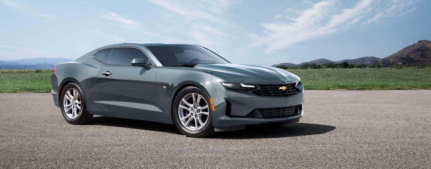 A gray 2023 Chevy Camaro is shown parked on gravel.