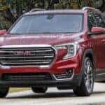 A red 2023 GMC Terrain SLT is shown driving on a trail after visiting a Fayetteville GMC dealer.