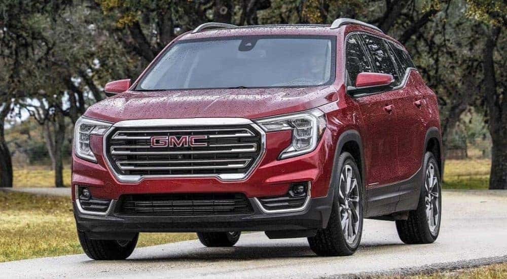 A red 2023 GMC Terrain SLT is shown driving on a trail after visiting a Fayetteville GMC dealer.