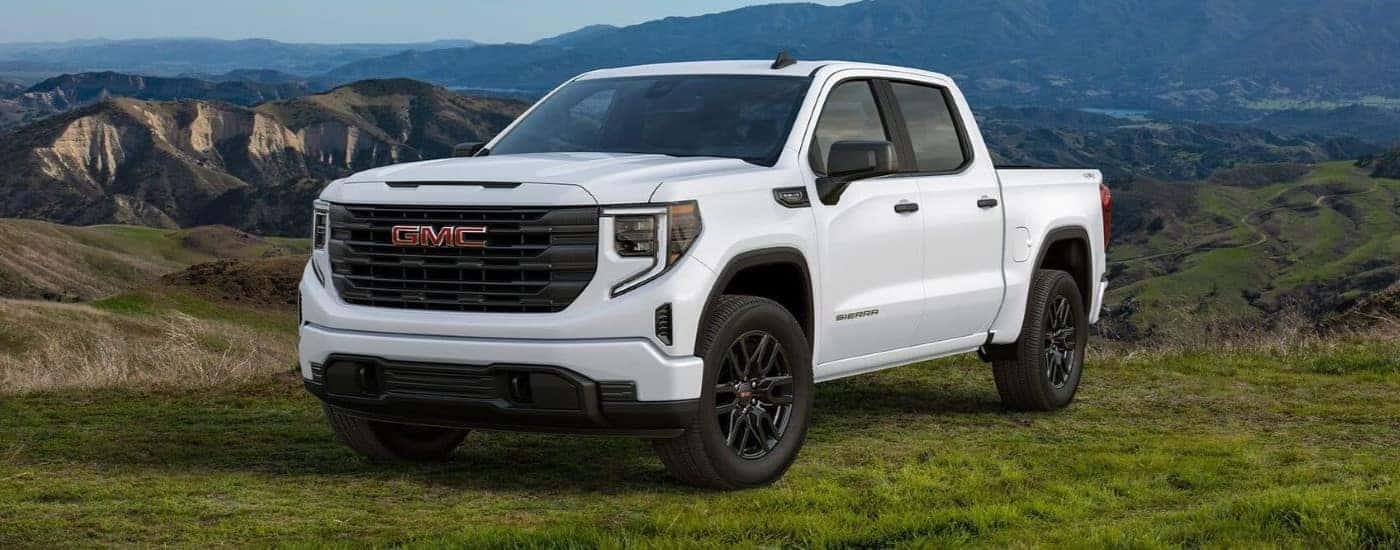 A white 2024 GMC Sierra 1500 SLE is shown overlooking mountains after leaving a Fayetteville GMC dealer.