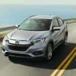 A silver 2020 Honda HR-V EX-L is driving on a coastal highway.