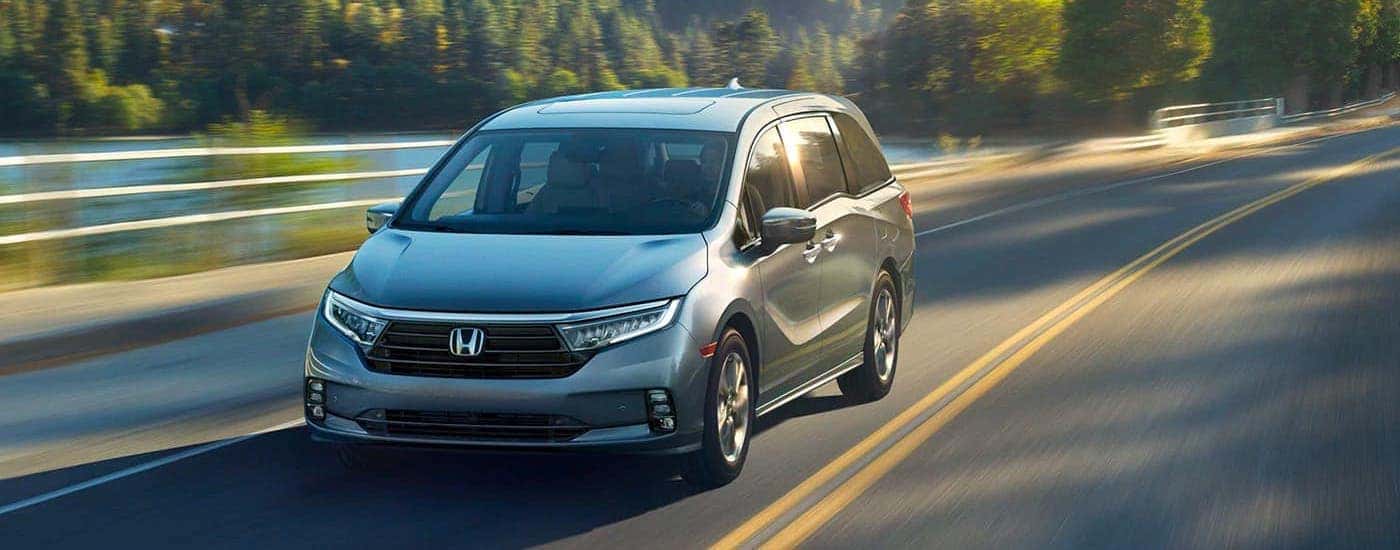 A green 2021 Honda Odyssey Elite is shown driving on a highway from the front.