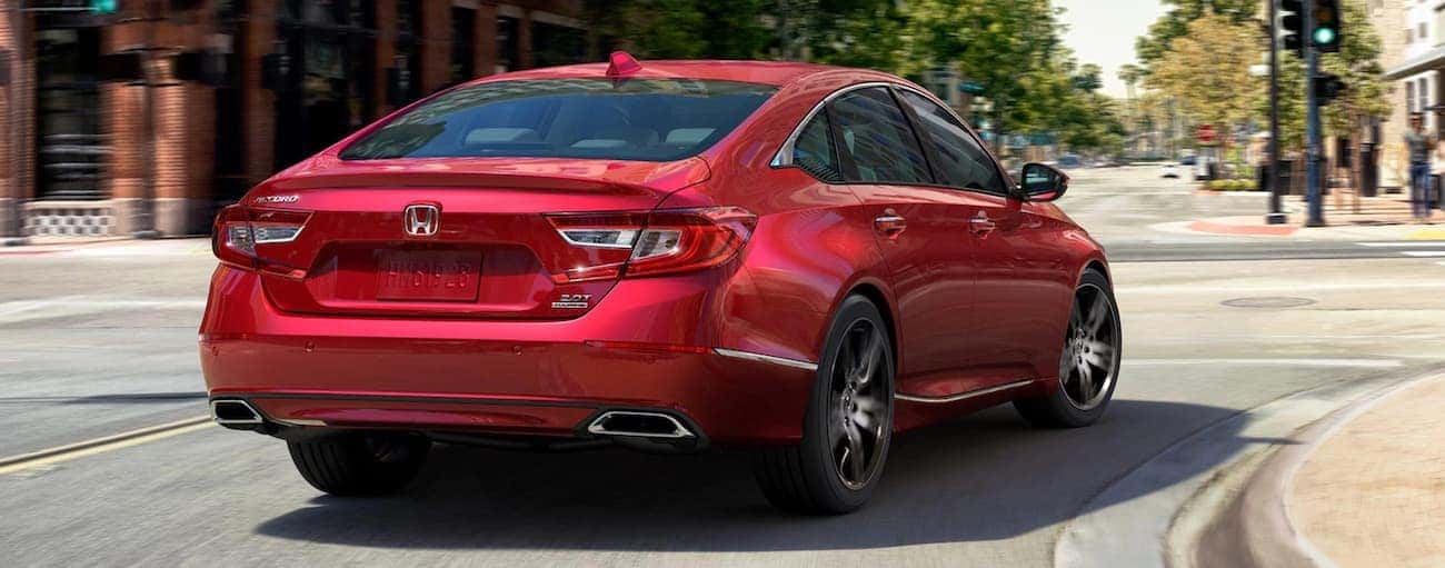 A red 2021 Honda Accord 2.0T Touring is driving on a city street, shown from the rear.