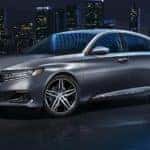 A silver 2020 Honda Accord is shown at night with a city scape in the background.
