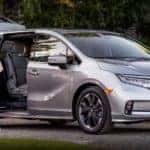 A silver 2022 Honda Odyssey Elite is shown from the side with the side door open next to a family.