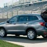 A family is shown putting sports gear into the cargo area of a silver 2020 Honda Pilot LX.