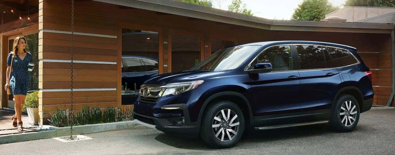 A blue 2022 Honda Pilot is shown parked in a modern driveway.