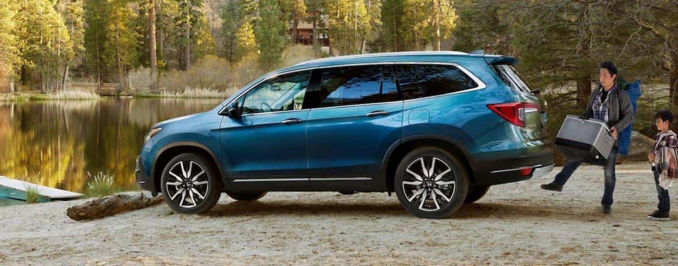 A blue 2022 Honda Pilot Elite is shown parked near a body of water.