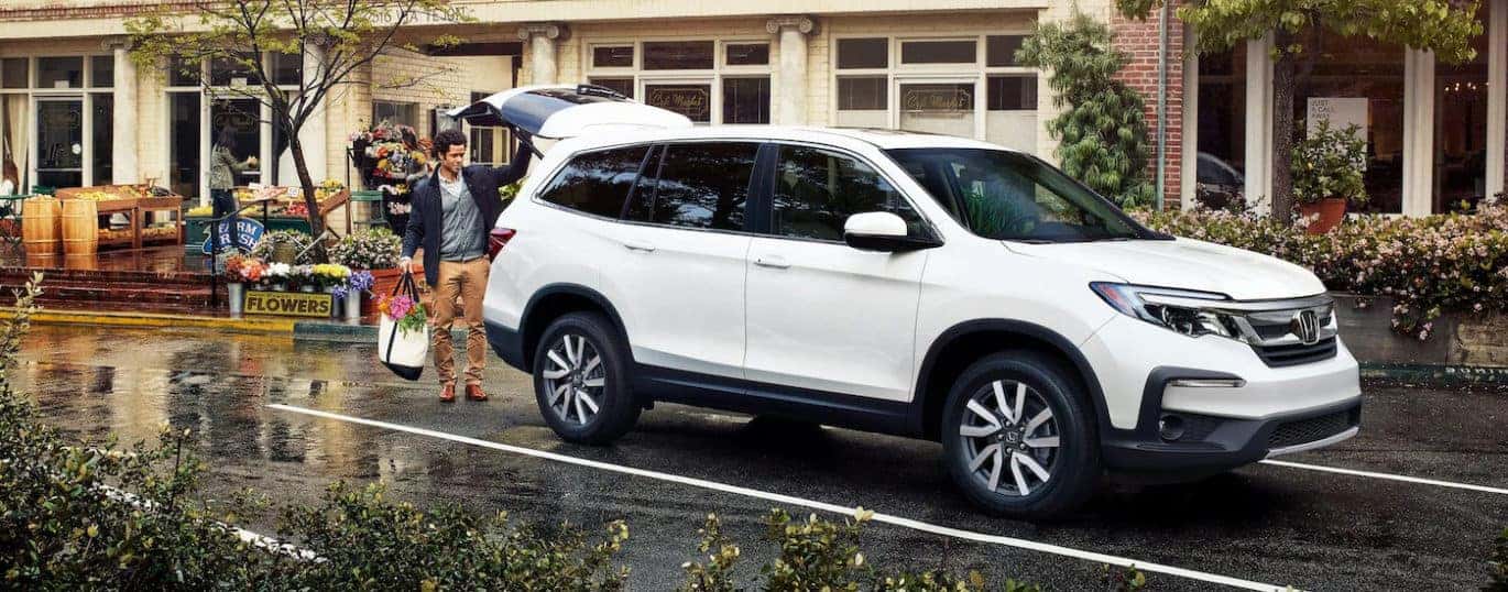 A white 2022 Honda Pilot EX-L is shown parked near a storefront.