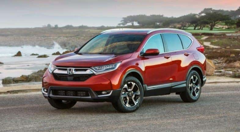A red 2019 Honda CR-V is shown parked in front of a body of water.