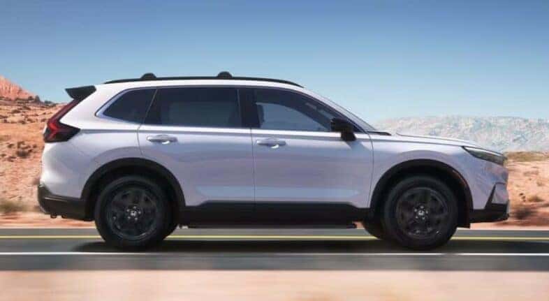 A white 2024 Honda CR-V Sport Touring Hybrid for sale is shown driving on a highway after visiting a Honda CR-V Hybrid for sale.
