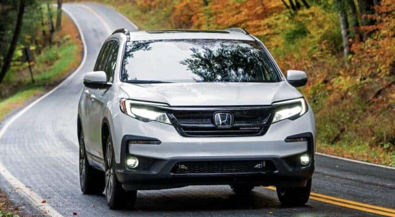 A white 2022 Honda Pilot Black Edition is shown driving to visit a used Honda dealership near Greece.