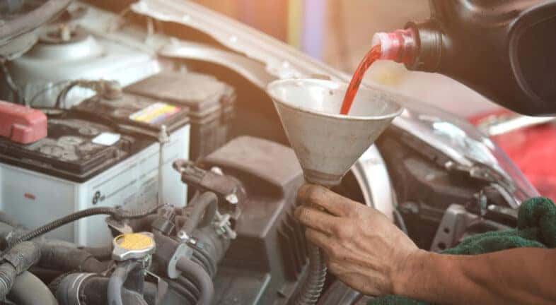 A mechanic pouring transmission fluid into a funnel at a transmission shop.