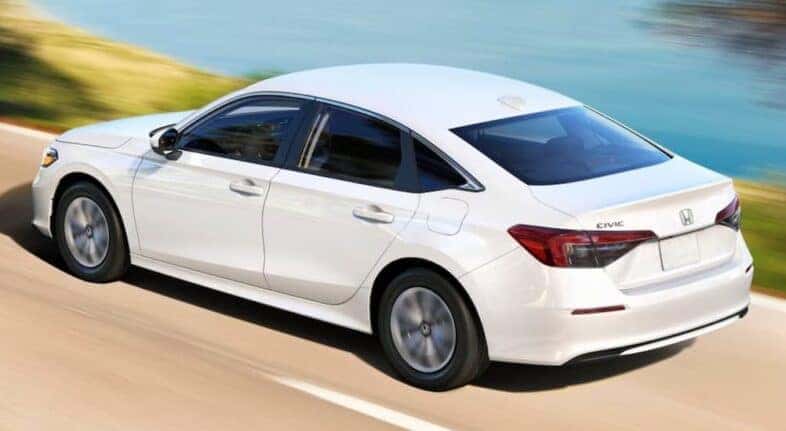 A white 2025 Honda Civic LX is shown driving after viewing a Honda Civic for sale.