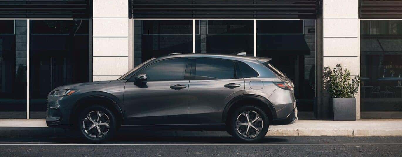A silver 2025 Honda HR-V EX-L is parked on a city street.
