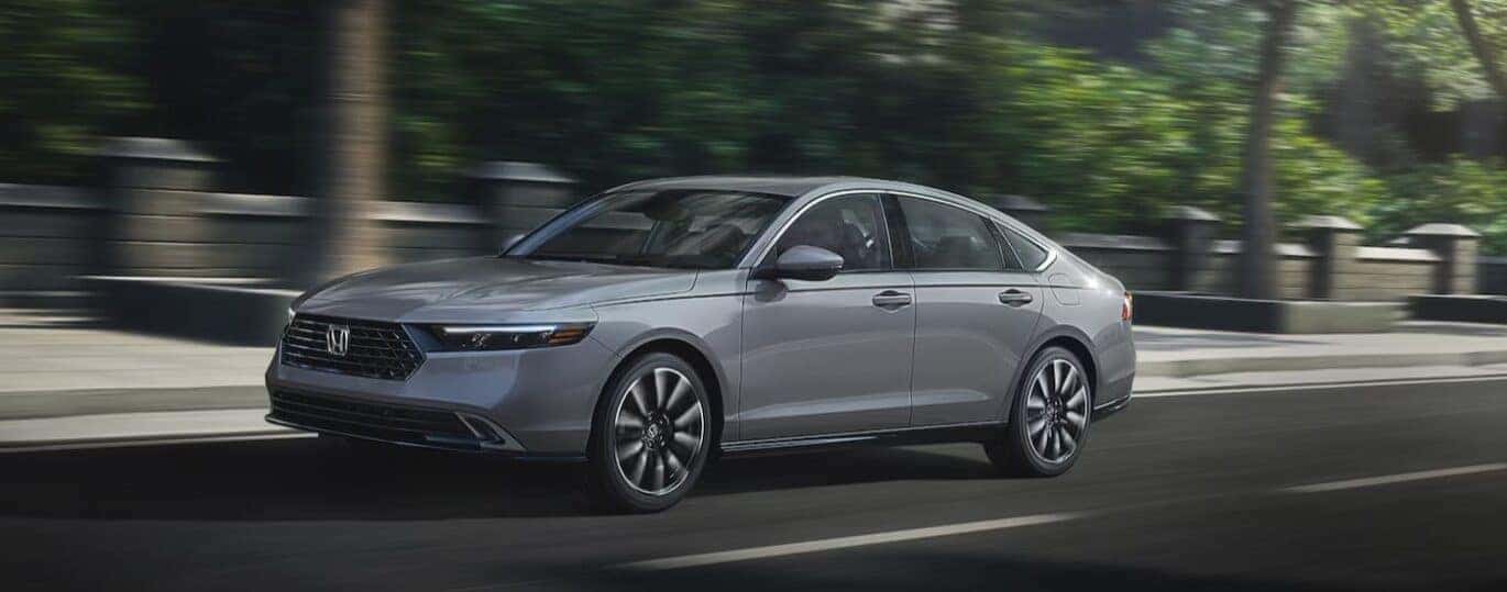 A gray 2025 Honda Accord Hybrid is shown driving on a city street.