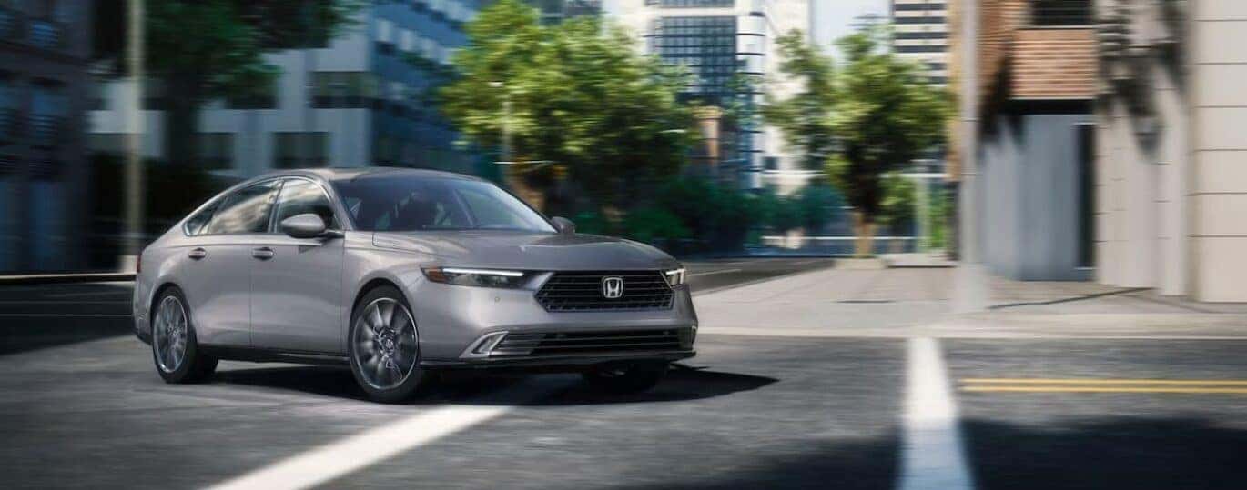 A gray 2025 Honda Accord Hybrid is shown driving on a city street.