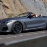 A silver 2024 BMW 8 Series is shown from a side angle while driving from a BMW dealer near Plano.