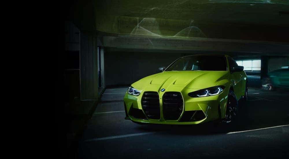 A yellow 2024 BMW M4 Competition is shown parked in a garage.
