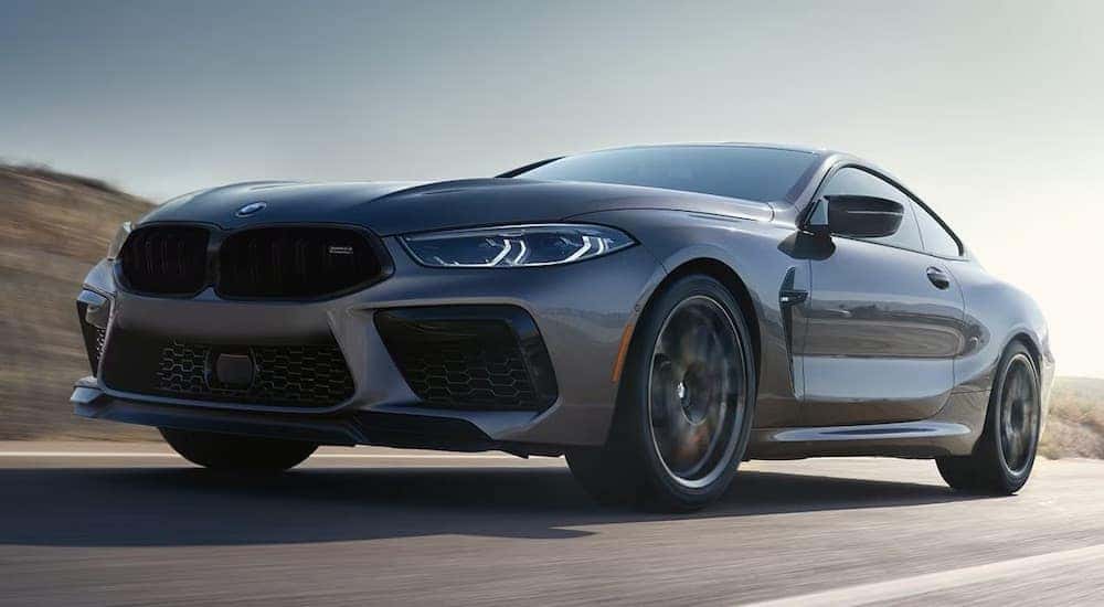 A grey 2024 BMW M8 Competition is shown driving.