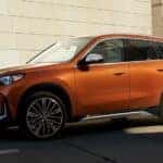 An orange 2024 BMW X1 parked outside a BMW dealer near Plano.