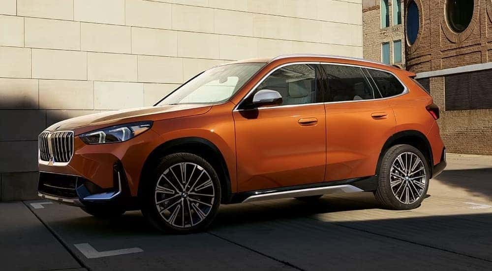 An orange 2024 BMW X1 parked outside a BMW dealer near Plano.