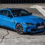 A blue 2024 BMW M4 is shown from the front at an angle after leaving a BMW dealer near me.