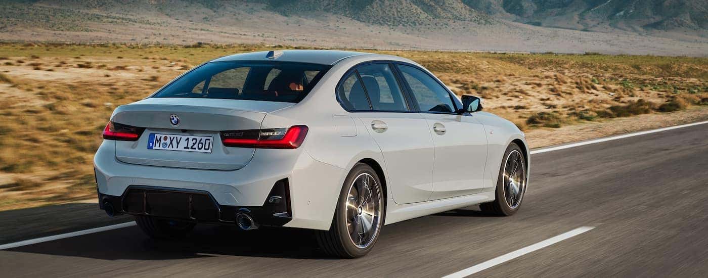 A grey 2024 BMW 3 Series is shown from the rear at an angle.