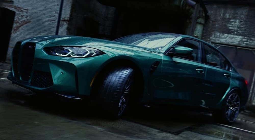 A green 2024 BMW M3 Sedan is shown parked near a BMW M Certified dealer.