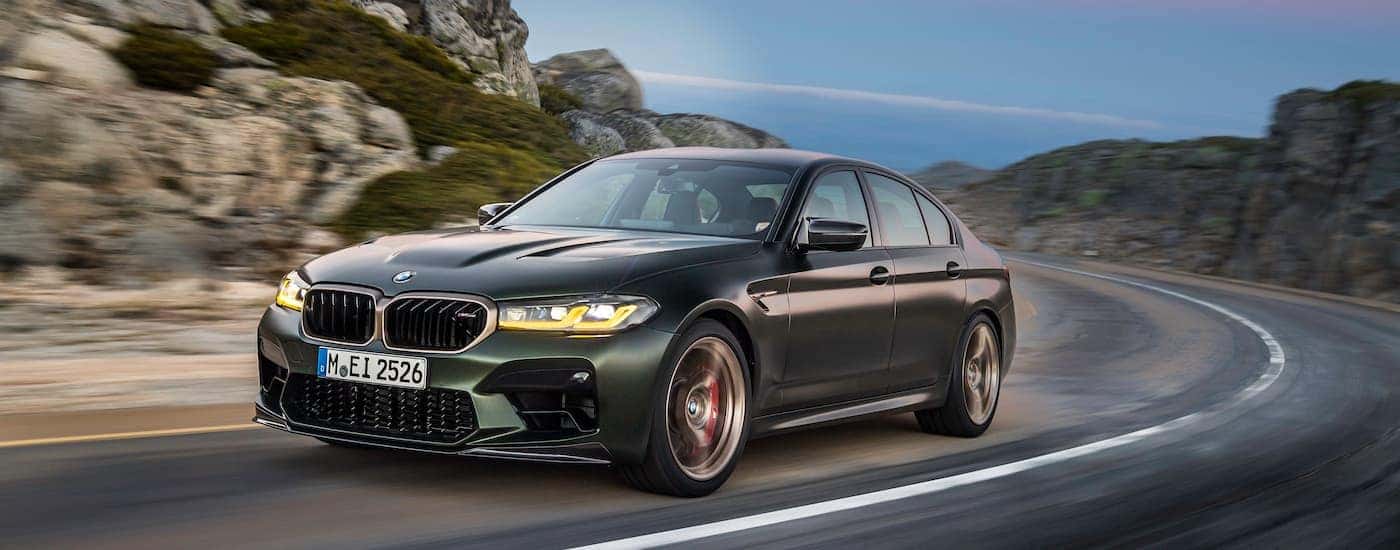 A green 2024 BMW M5 CS is shown from the front at an angle.