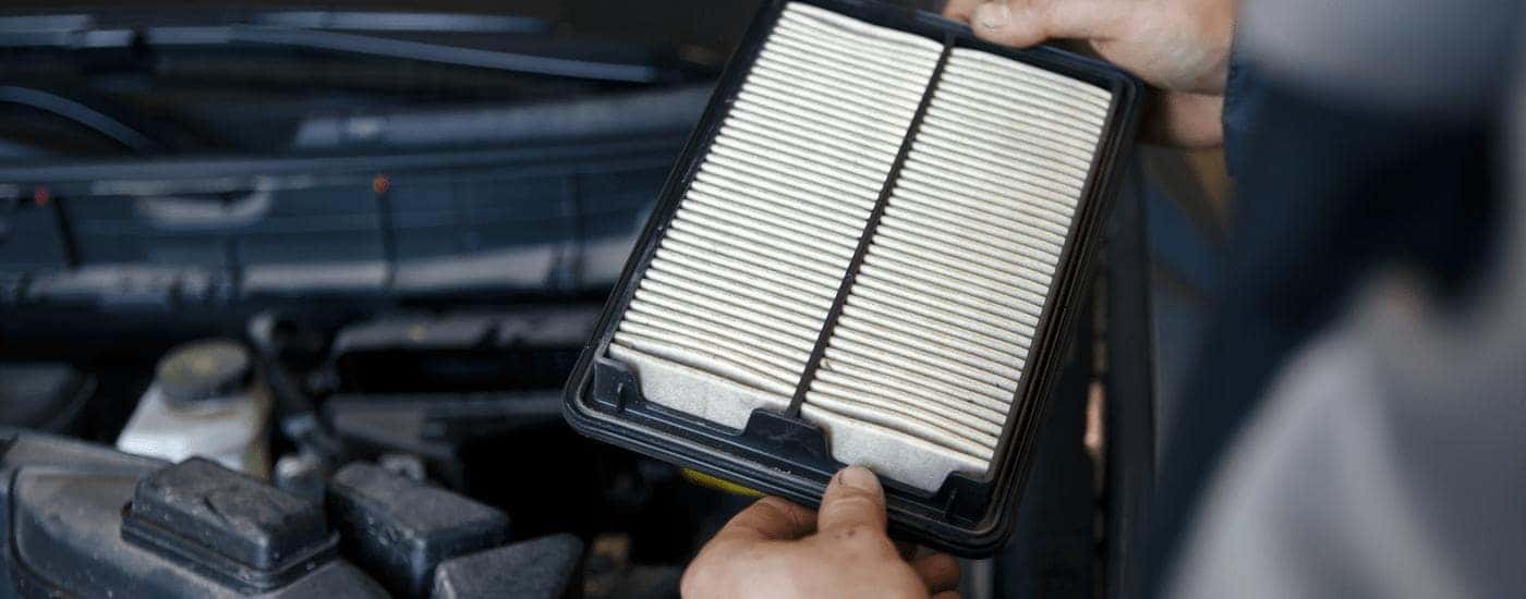 A mechanic is replacing an air filter in a vehicle.