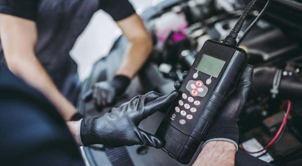 A mechanic is shown using a code reader in an engine bay.