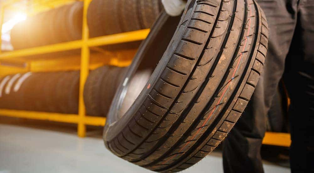 A mechanic is shown holding a tire.