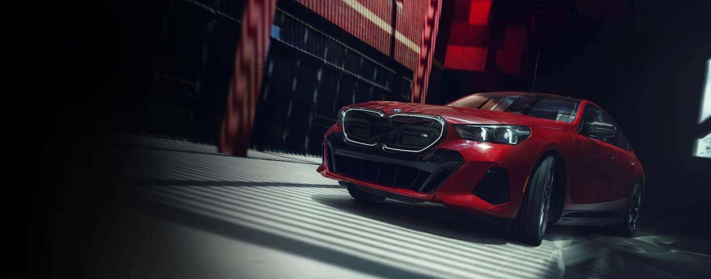 A red 2024 BMW i5 M60 driving in a city.