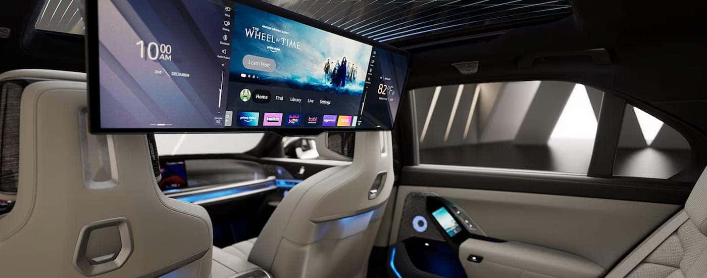 A view of the backseat interior of a 2024 BMW i7, including the large passenger facing infotainment screen.
