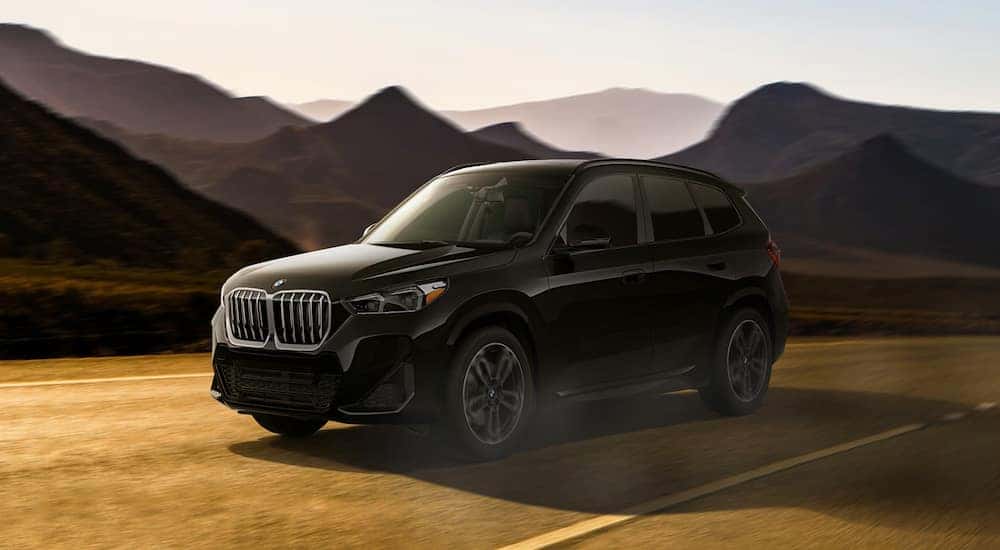 A black 2023 BMW X1 driving on a mountain road.