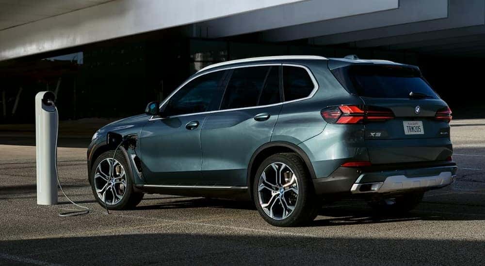 A grey 2025 BMW X5 is shown charging.