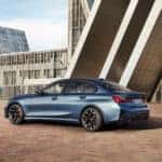 A blue 2025 BMW 3 Series is shown from the side.