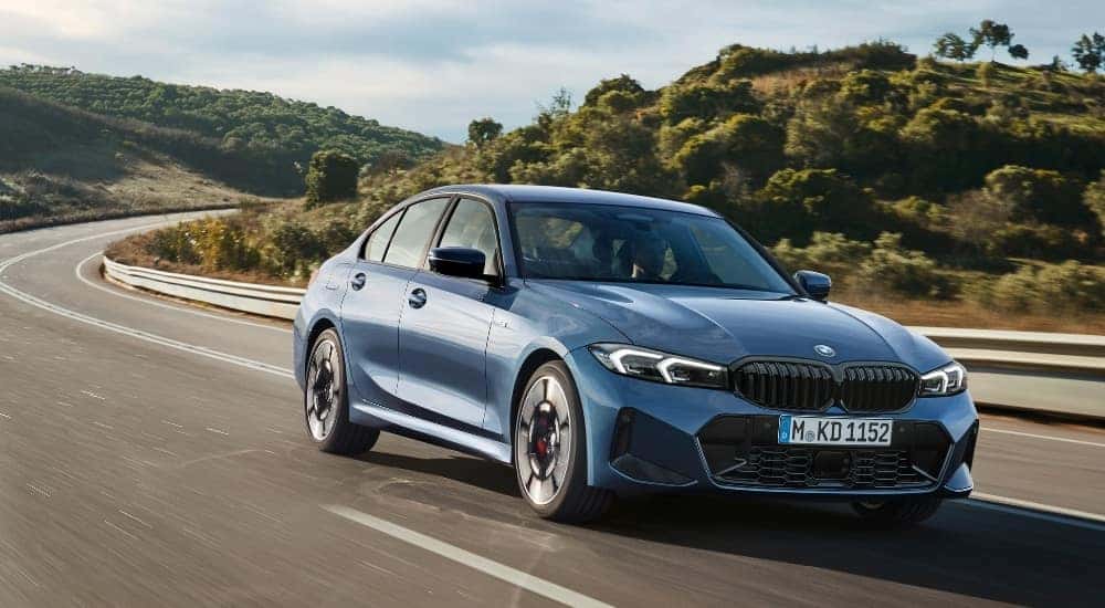 A blue 2025 BMW 3 Series for sale is shown from the front at an angle.