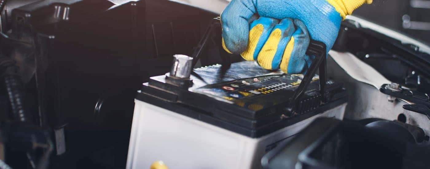 A technician is shown performing a car battery replacement.