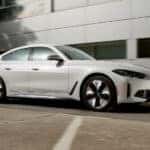 A popular BMW for sale near Dallas, a white 2024 BMW i4 Gran Coupe, is shown parked near a building.