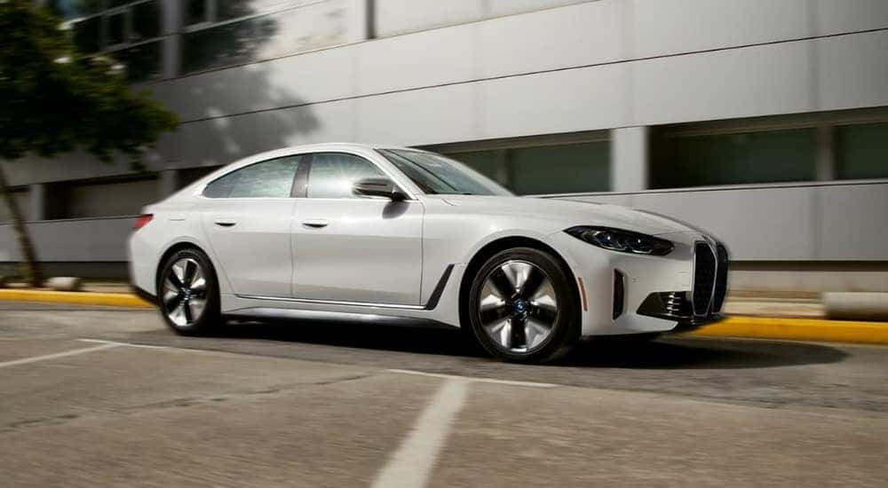 A popular BMW for sale near Dallas, a white 2024 BMW i4 Gran Coupe, is shown parked near a building.