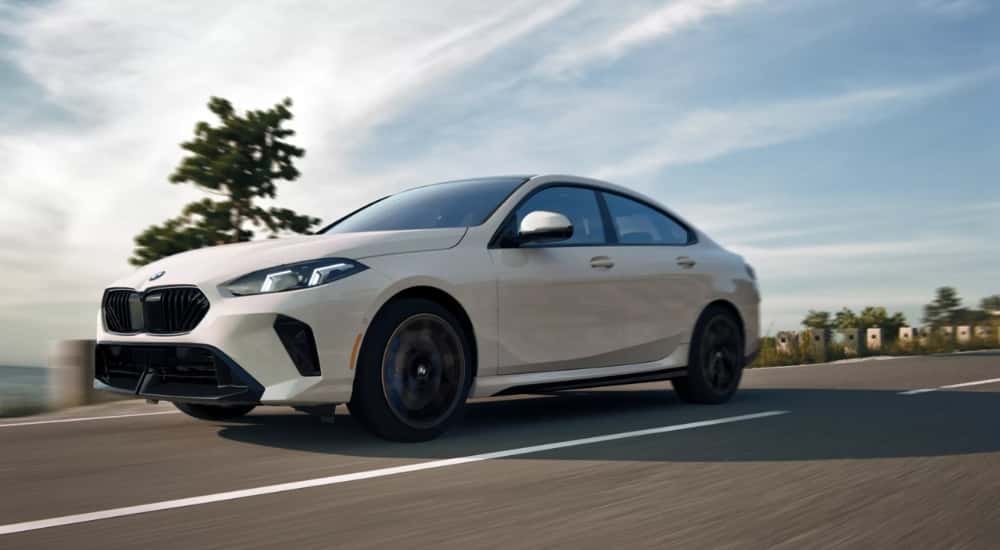A white 2025 BMW 2 Series Gran Coupe is shown driving on a cloudy day.