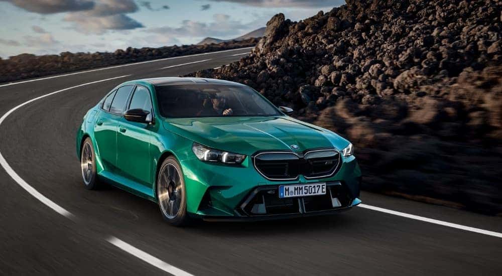 A green 2025 BMW M5 is shown from the front at an angle after leaving a dealer that has a BMW for sale.
