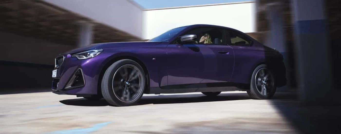 A purple 2023 BMW M240 is shown from the front at an angle after leaving a BMW dealer near Plano.