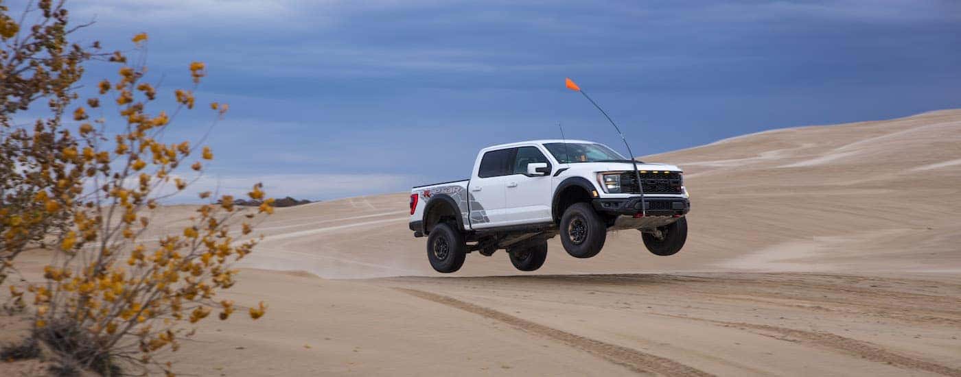A white 2024 Ford F-150 Raptor R from the side after leaving a dealer that has lifted trucks for sale.
