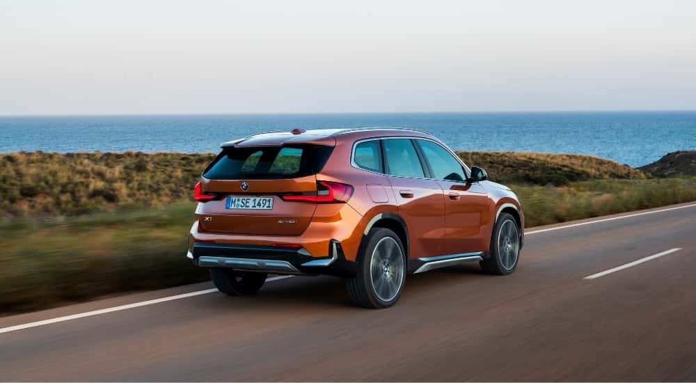 An orange 2025 BMW X1 from the rear at an angle.